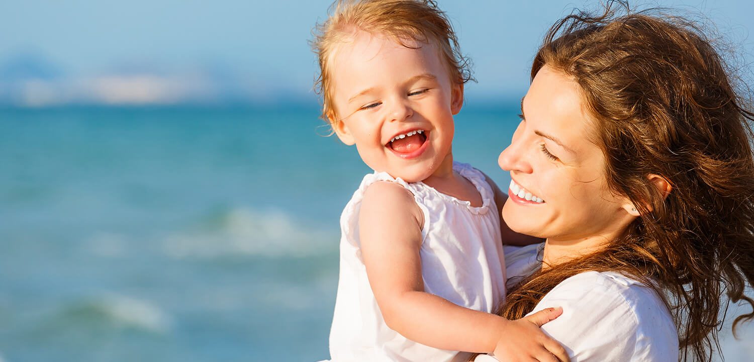 Smiling mother and daughter by the sea